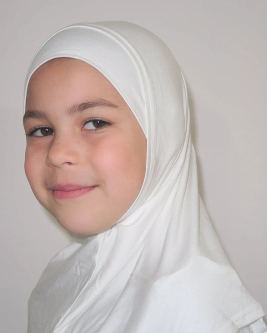Young girl wearing a white hijab against a plain background